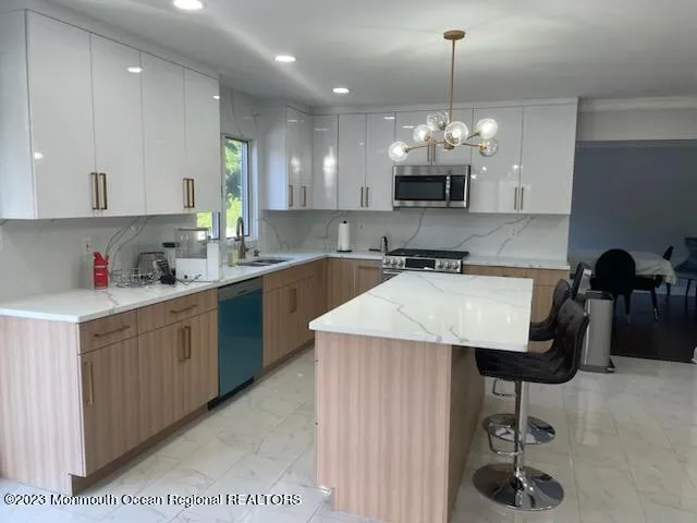 a large kitchen with kitchen island granite countertop a stove a sink a counter top space and cabinets