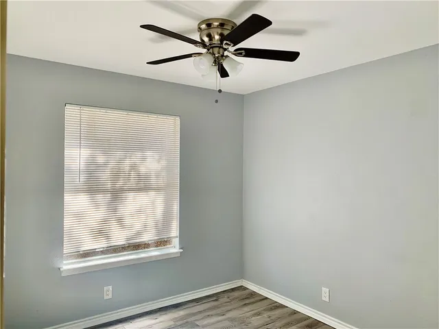 an empty room with a window and a fan