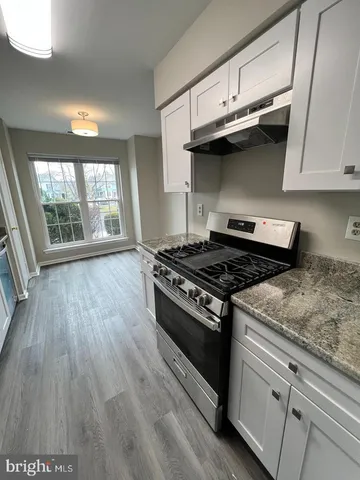 a kitchen with granite countertop wooden floors and stainless steel appliances