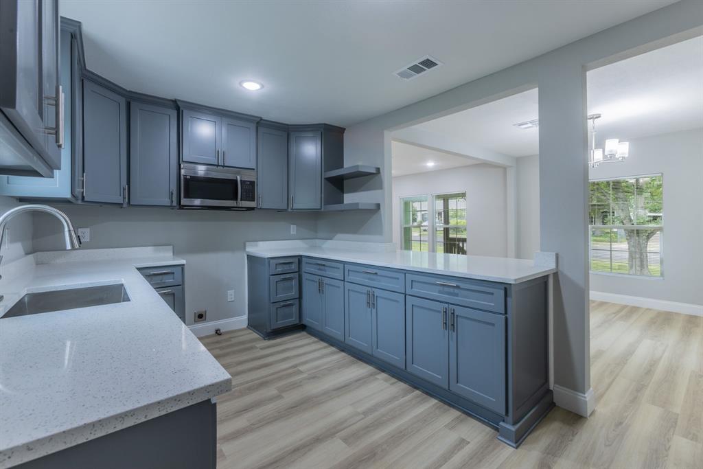 2816 Summer Avenue Waco, TX 76708 - Photo 5 of 16 a kitchen with wooden cabinets a sink a stove a window and appliances