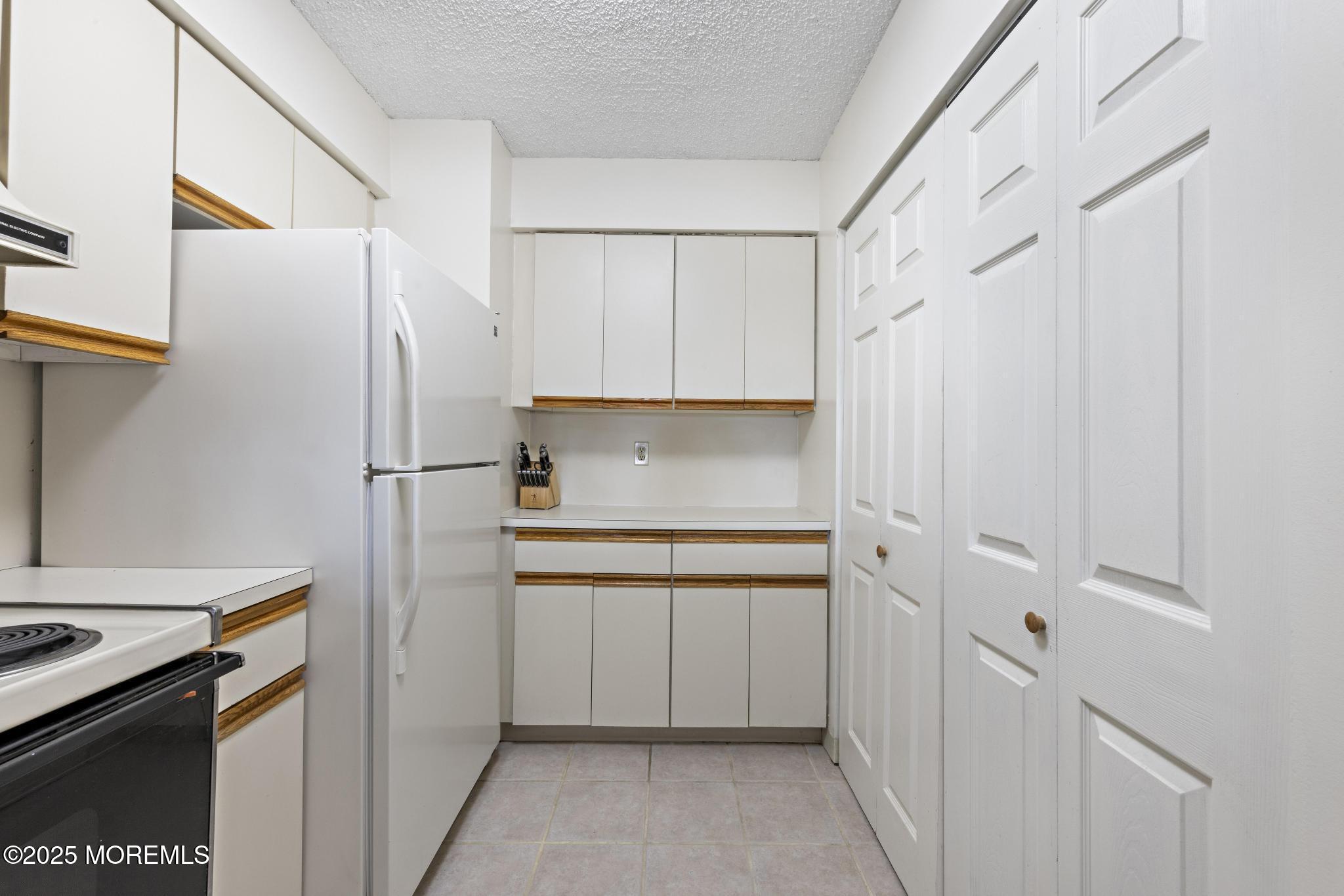 32 Center Avenue, Unit 17 Atlantic Highlands, NJ 07716 - Photo 11 of 27 a kitchen with cabinets and a refrigerator