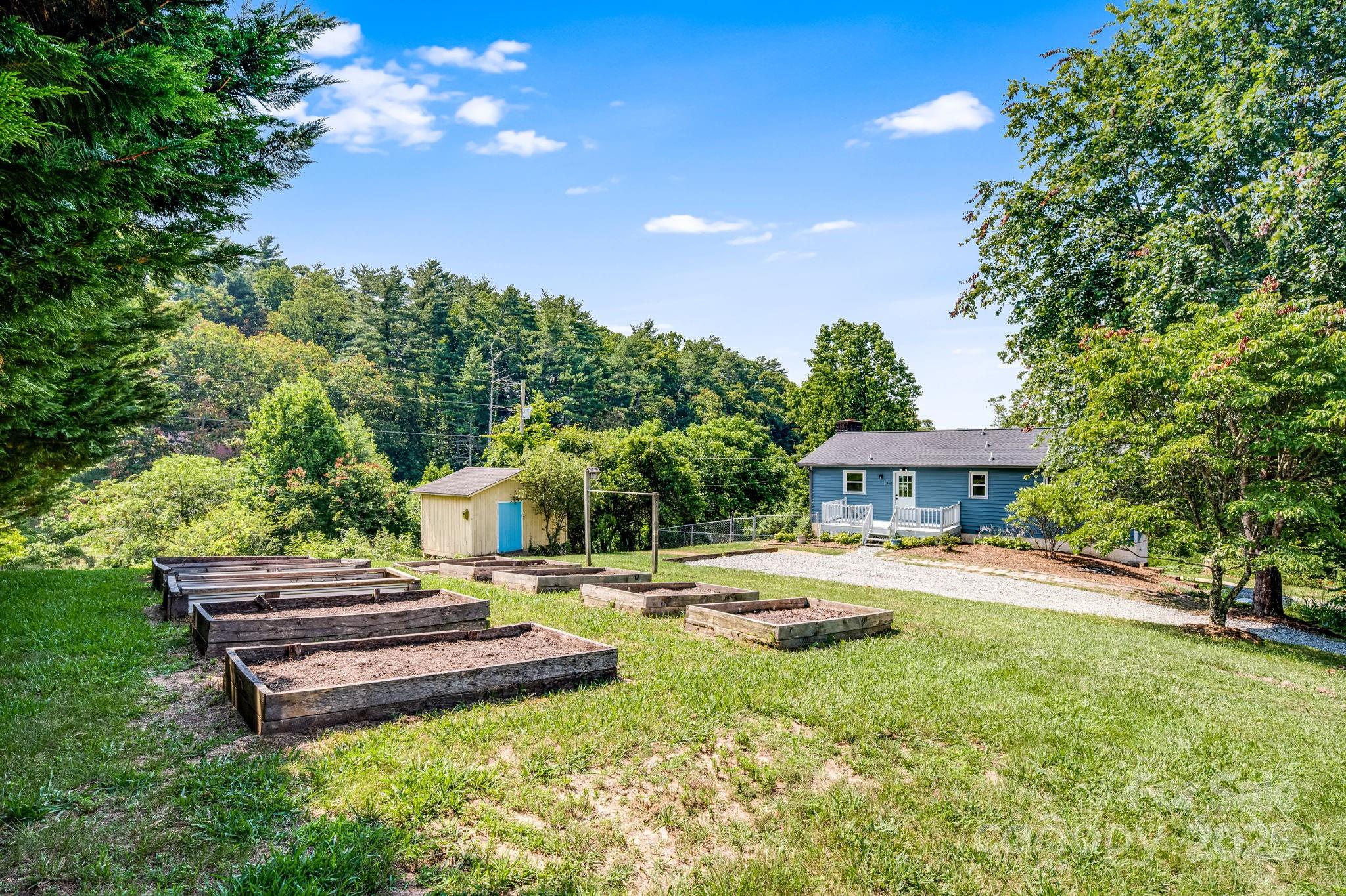 1360 Jupiter Road Weaverville, NC 28787 - Photo 2 of 39 a backyard of a house with table and chairs under a large tree