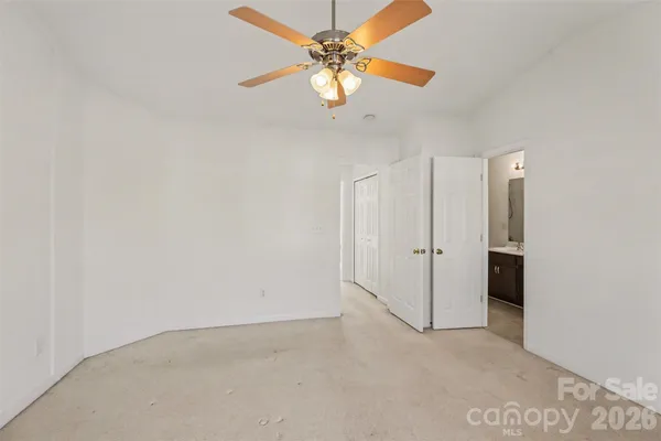 an empty room with a chandelier fan and windows