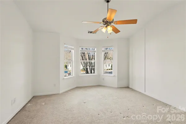 an empty room with windows and fan