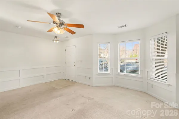 an empty room with windows and fan