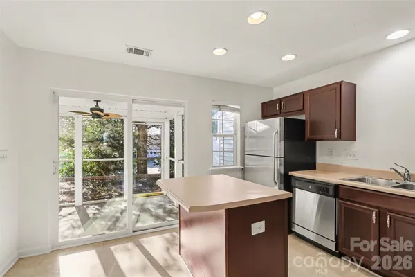 a kitchen that has a refrigerator a stove a sink and a dining table with wooden floor