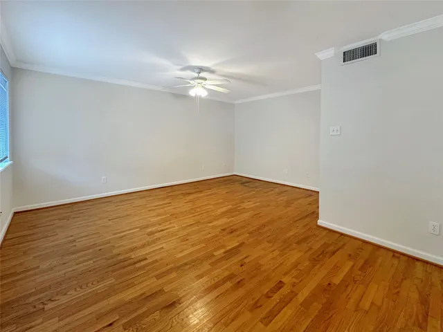 an empty room with wooden floor and fan