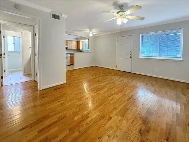 a view of empty room with wooden floor and fan