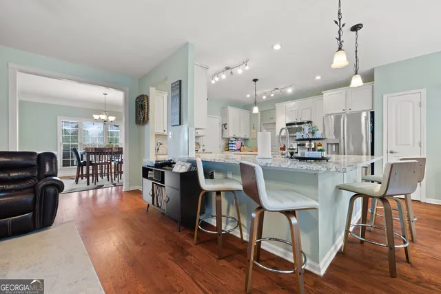 a kitchen with stainless steel appliances kitchen island granite countertop wooden floors and white cabinets