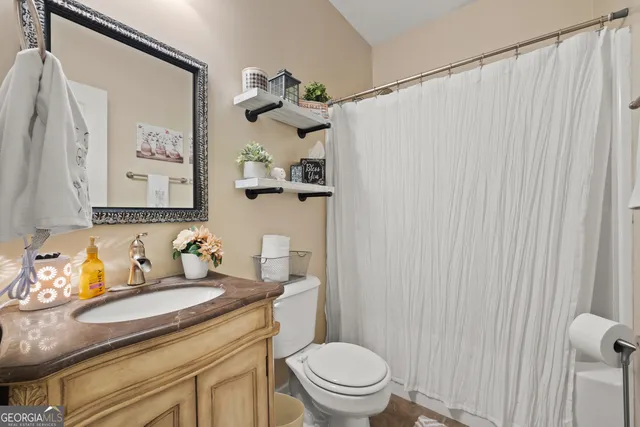 a bathroom with a granite countertop sink vanity mirror and toilet