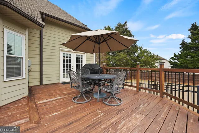 a view of a roof deck with table and chairs under an umbrella with wooden floor and fence