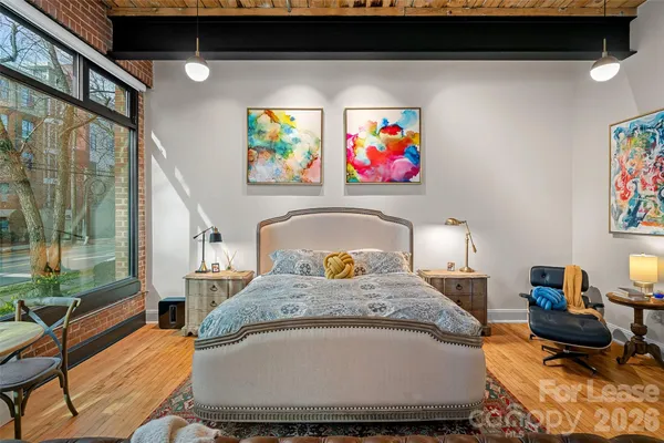 a spacious bedroom with a bed a couch and a large window
