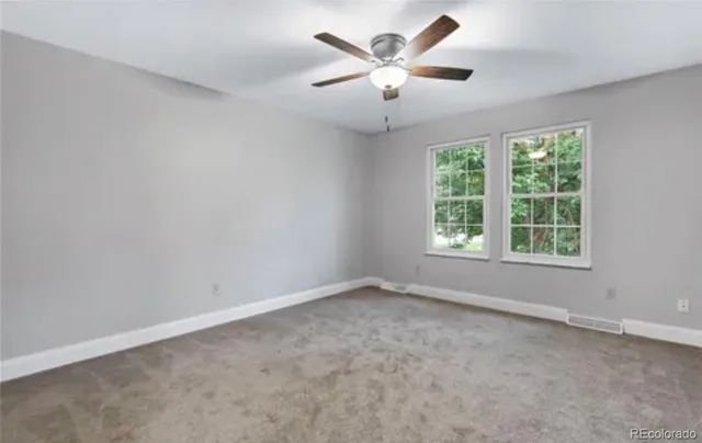an empty room with a chandelier fan and windows
