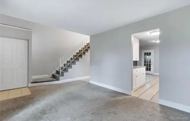 a view of an empty room with stairs and a kitchen