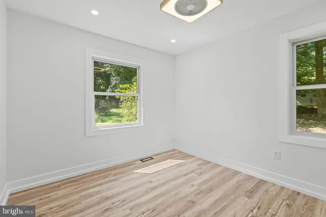 a view of an empty room with wooden floor and closet