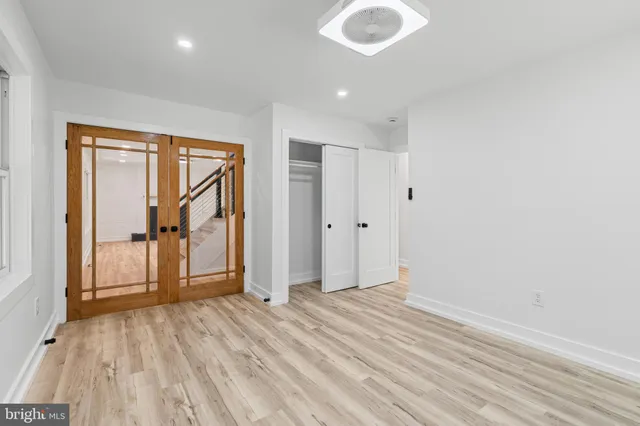 a view of empty room with wooden floor and fan
