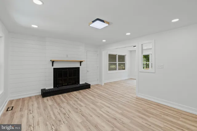 a view of an empty room with wooden floor and windows