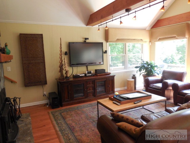 378 Howard's Creek Road Boone, NC 28607 - Photo 10 of 35 a living room with furniture a flat screen tv and a floor to ceiling window