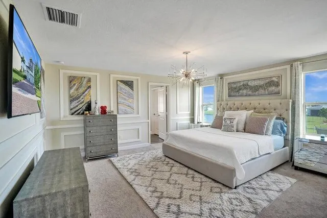 a spacious bedroom with a large bed and a chandelier