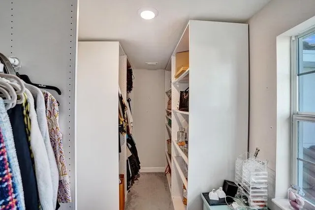 a view of walk in closet with clothes and shoes