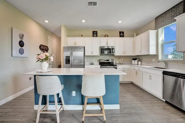 a kitchen with stainless steel appliances a dining table chairs microwave and sink