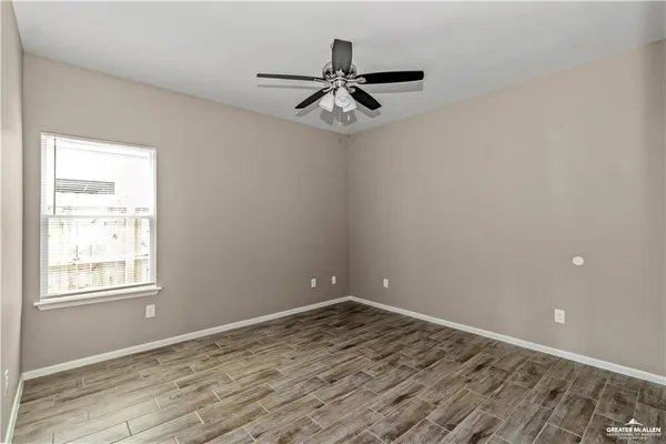 a view of empty room with wooden floor and fan