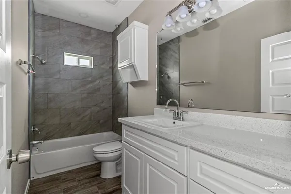 a bathroom with a granite countertop sink a toilet and shower