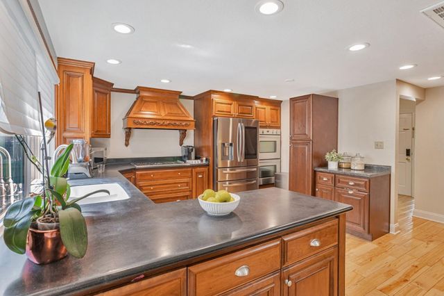 a kitchen with stainless steel appliances granite countertop a sink a counter space and cabinets