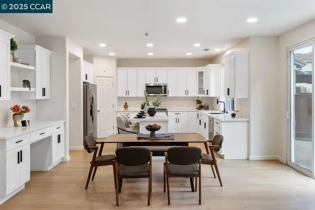 a kitchen with stainless steel appliances granite countertop a stove a refrigerator a microwave a dining table and chairs