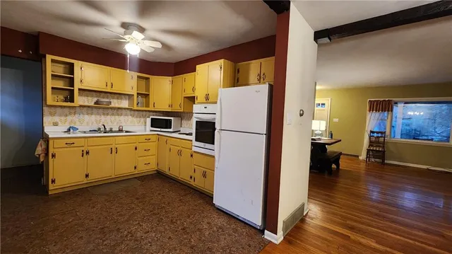 a kitchen with a refrigerator a stove cabinets dining table and chairs