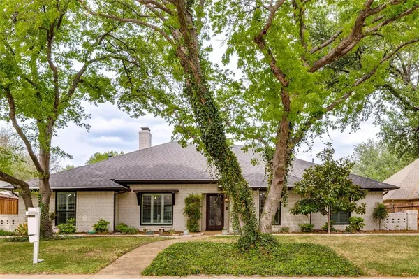 a front view of a house with a garden and trees