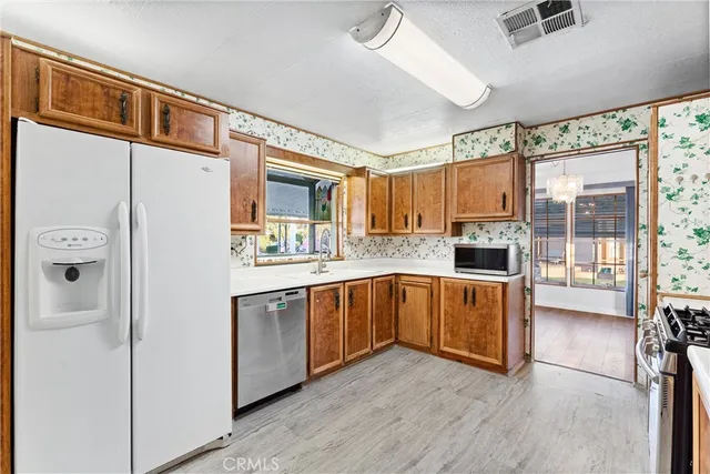 a kitchen with stainless steel appliances granite countertop a refrigerator a sink and white cabinets