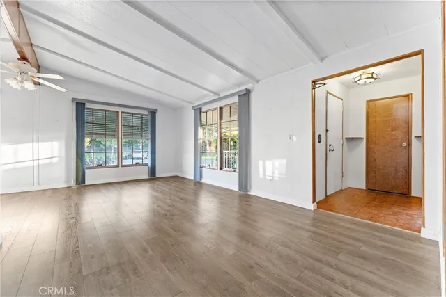 a view of a big room with wooden floor and windows