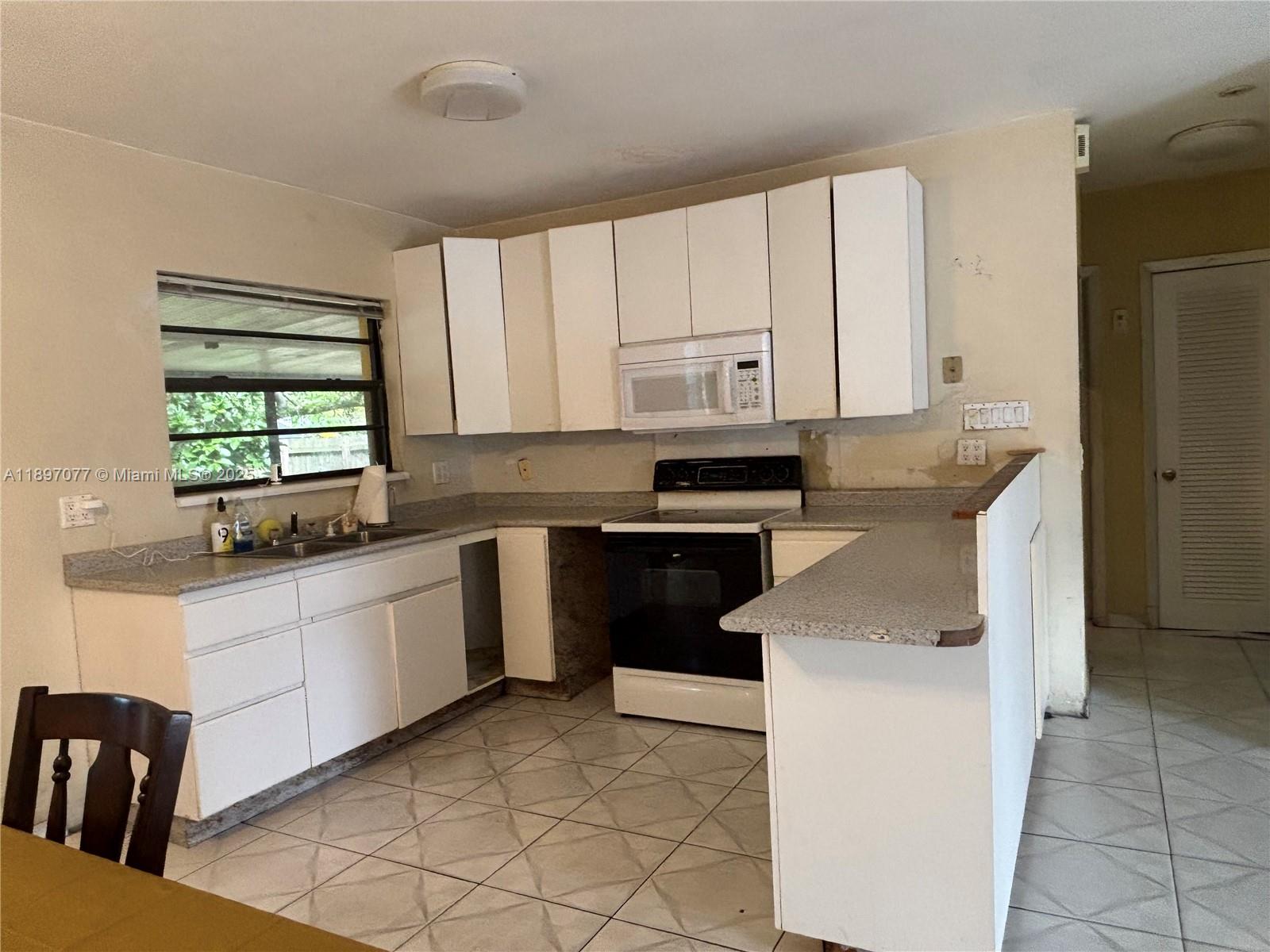 6261 Southwest 6th Street Miami, FL 33144 - Photo 7 of 29 a kitchen with granite countertop white cabinets and white appliances