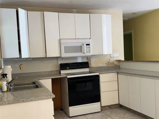 a kitchen with granite countertop white cabinets and white appliances