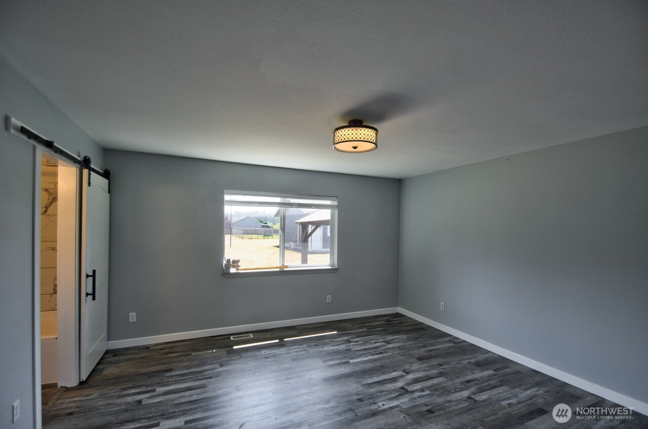8603 194th Avenue Southwest Rochester, WA 98579 - Photo 19 of 32 an empty room with wooden floor and windows