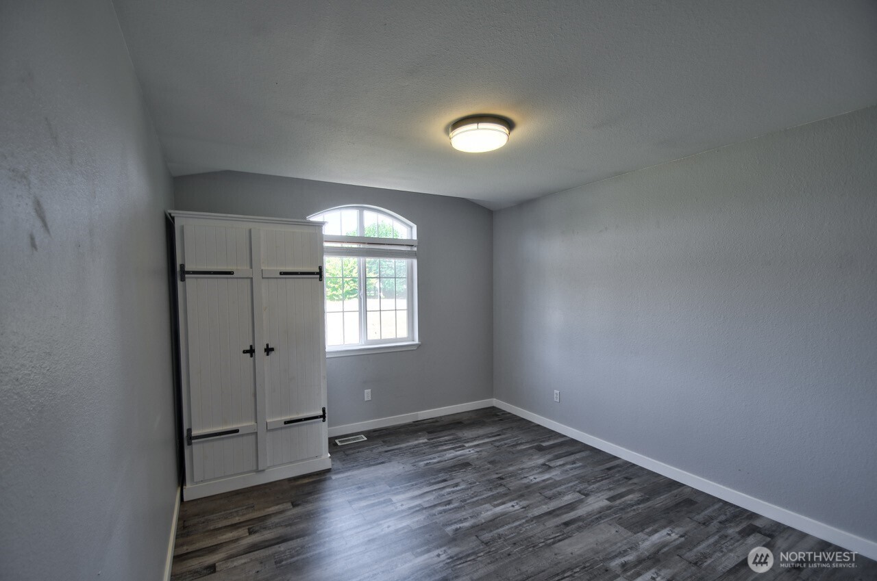 8603 194th Avenue Southwest Rochester, WA 98579 - Photo 23 of 32 an empty room with wooden floor and windows