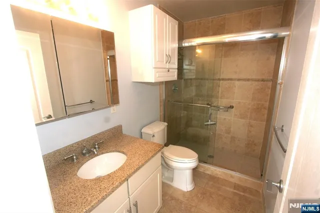 a bathroom with a granite countertop sink toilet and shower