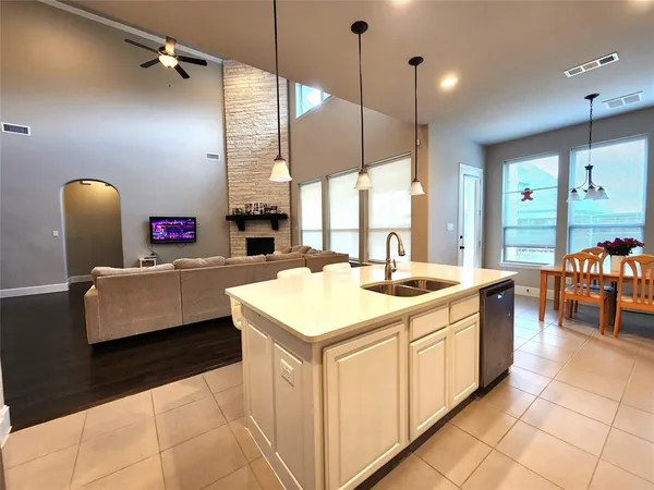 a kitchen with stainless steel appliances kitchen island granite countertop a sink a counter top space a dining table a chandelier and a view of living room