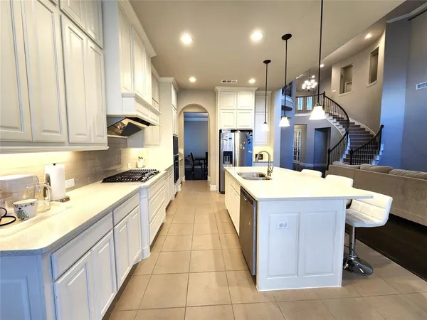 a large kitchen with stainless steel appliances kitchen island granite countertop a sink a stove and a refrigerator