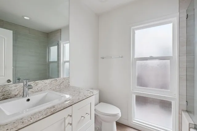 a bathroom with a granite countertop sink toilet and mirror