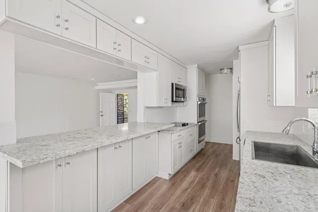a large white kitchen with a sink and cabinets