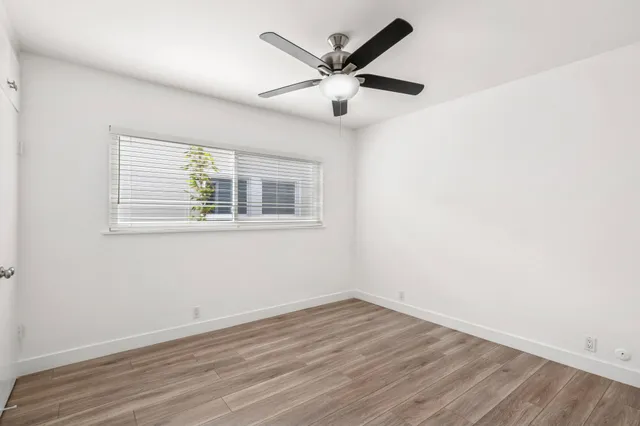 an empty room with wooden floor and ceiling fan