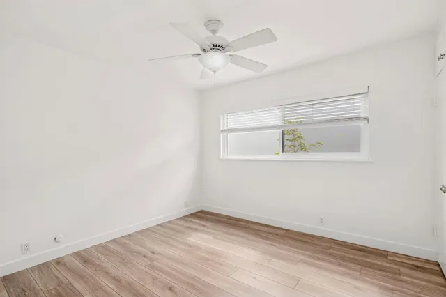an empty room with a window and ceiling fan