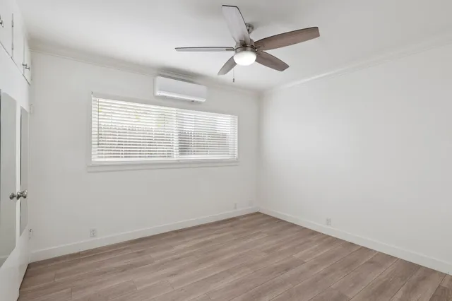 an empty room with wooden floor fan and windows