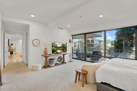 a spacious bedroom with a large bed and a flat tv screen