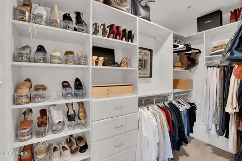 a view of walk in closet with clothes and shoes