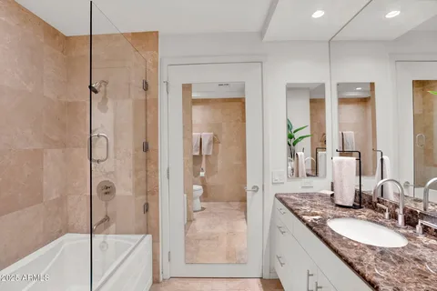 a bathroom with a granite countertop tub shower sink and mirror