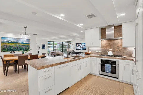 a kitchen with stainless steel appliances granite countertop a sink a stove and a refrigerator