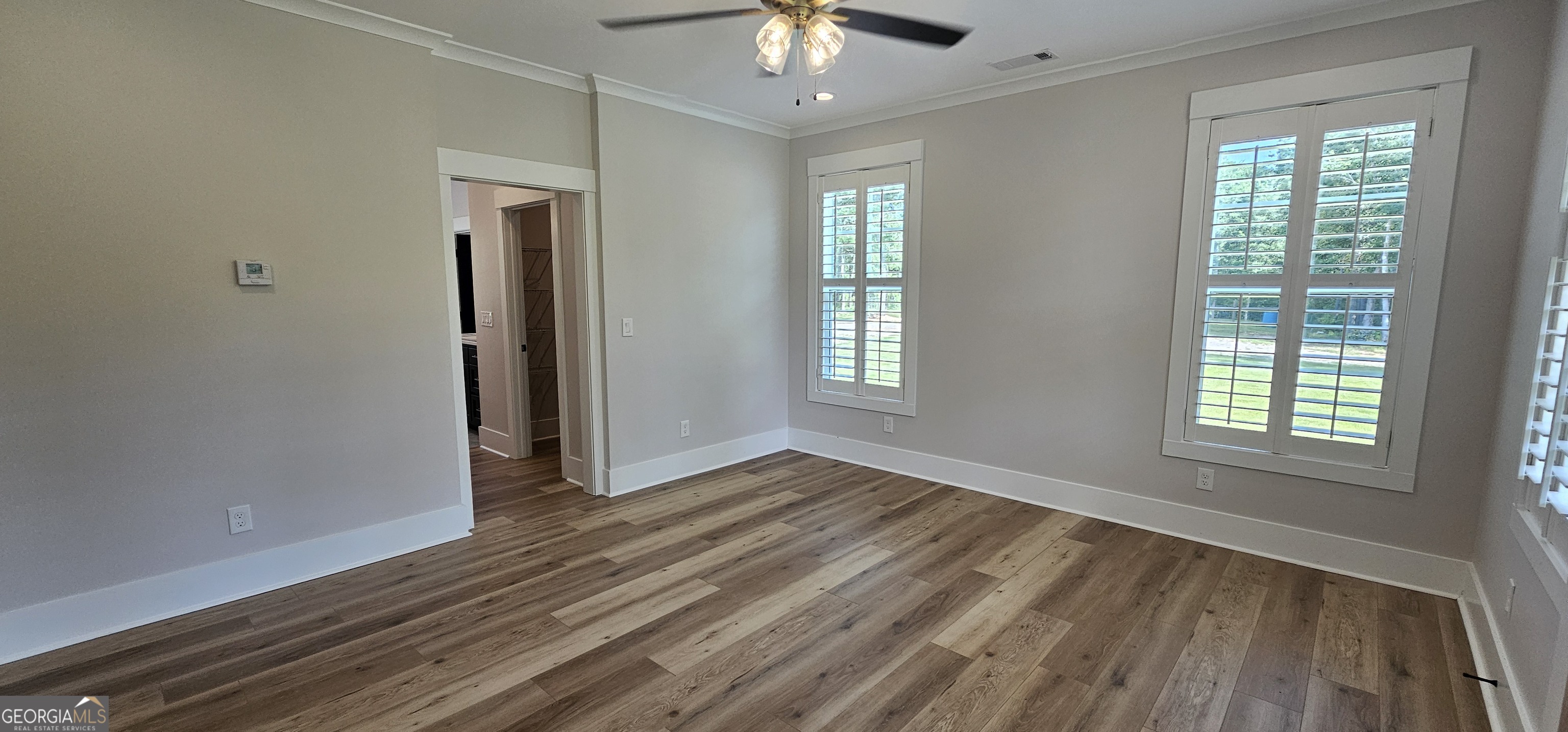 654 Liberty Hill Road Milner, GA 30257 - Photo 142 of 180 a view of an empty room with window chandelier fan and wooden floor